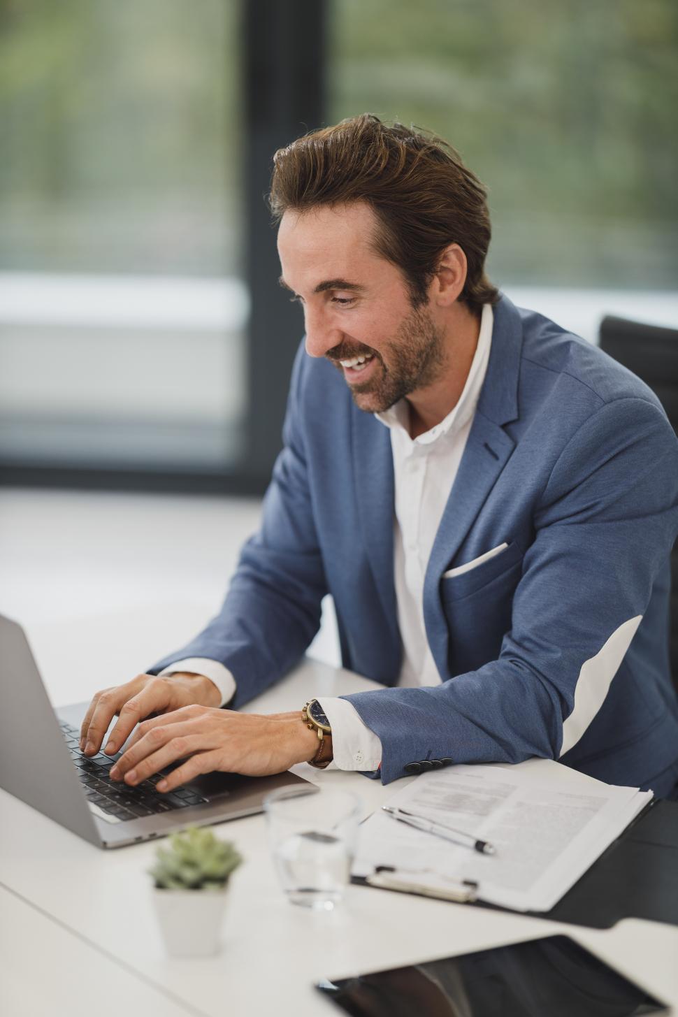 happy-male-executive-working-on-laptop